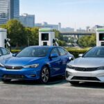 lineup of electric sedans parked with charging station in the background