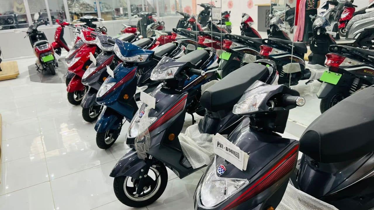 Electric two-wheeler being charged at an Indian dealership, representing the PM E-DRIVE subsidy scheme for electric scooters and bikes.