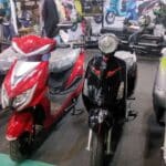 Electric two-wheeler being charged at an Indian dealership, representing the PM E-Drive subsidy scheme for electric scooters and bikes.