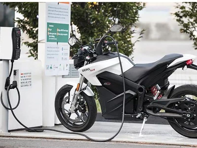 An electric motorcycle plugged into a public charging station in an Indian city