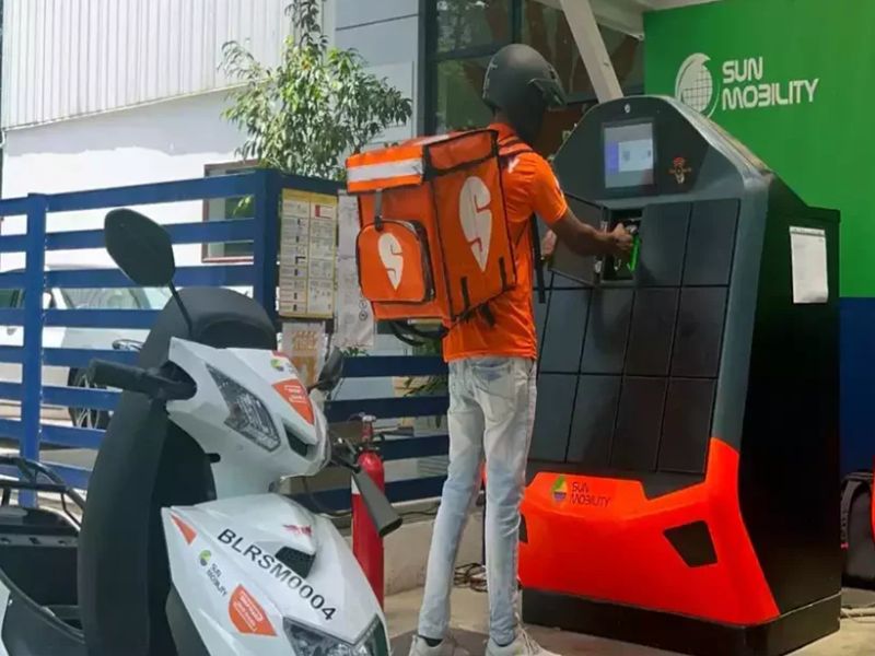 Electric scooter rider exchanging a depleted battery at a swap station