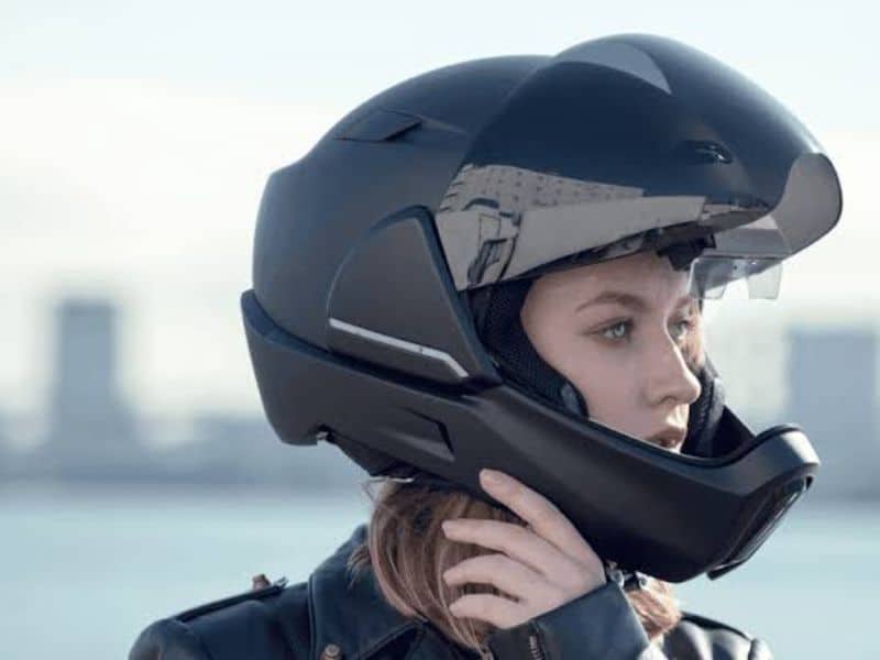 A rider checking the chin strap fit of a motorcycle helmet